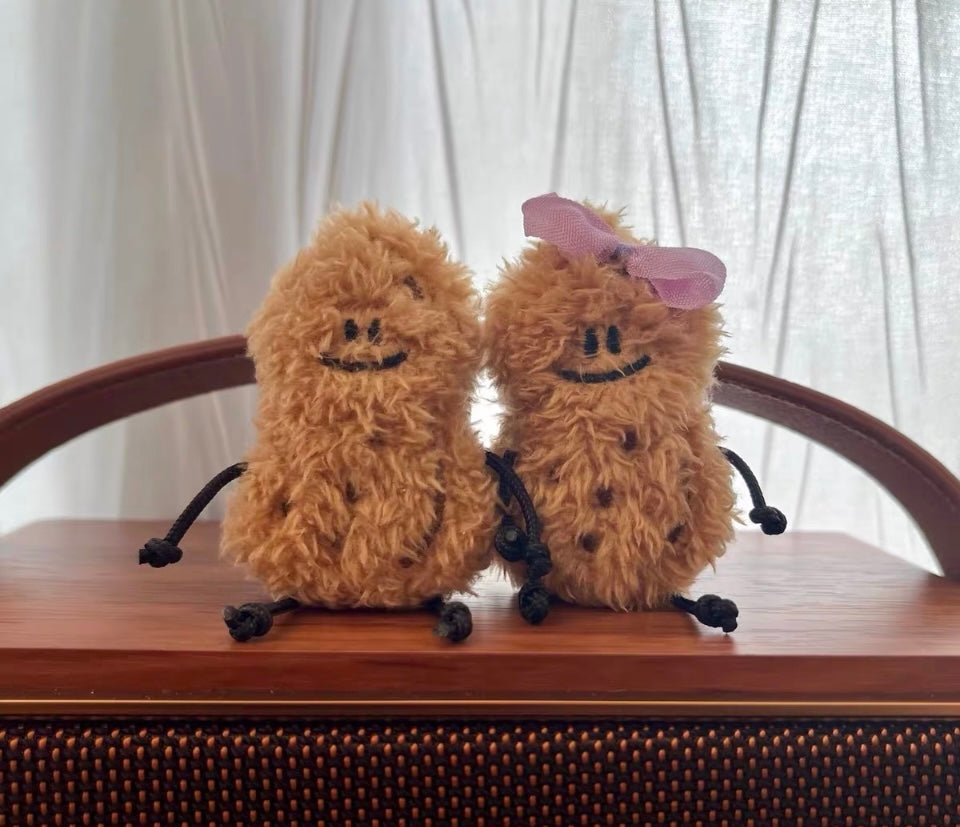 Two fluffy brown characters with black limbs on a wooden surface.