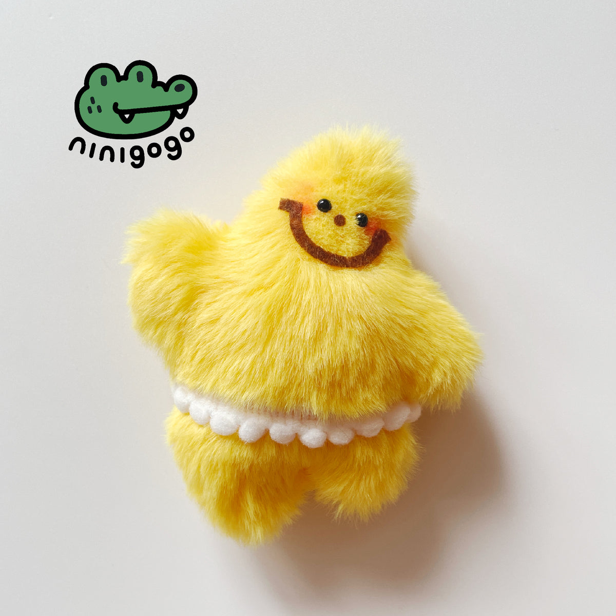 A soft plush star toy resembling a smiling face on a yellow background, with a blue nylon rope for a neck, and UK safety eyes branding.