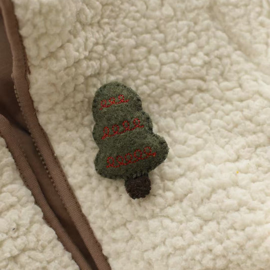 Green embroidered patch with text on a beige sherpa fabric background