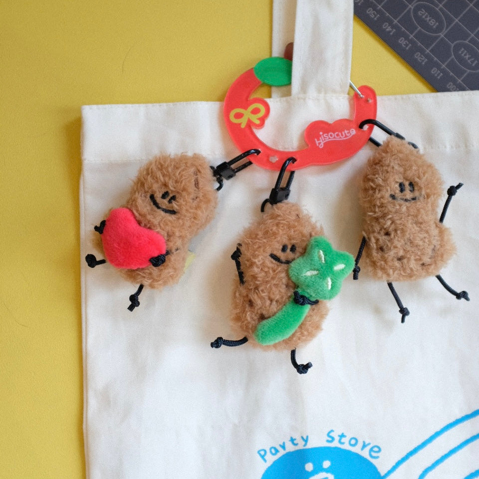 Three small plush figures on a white tote bag with a brand logo.
