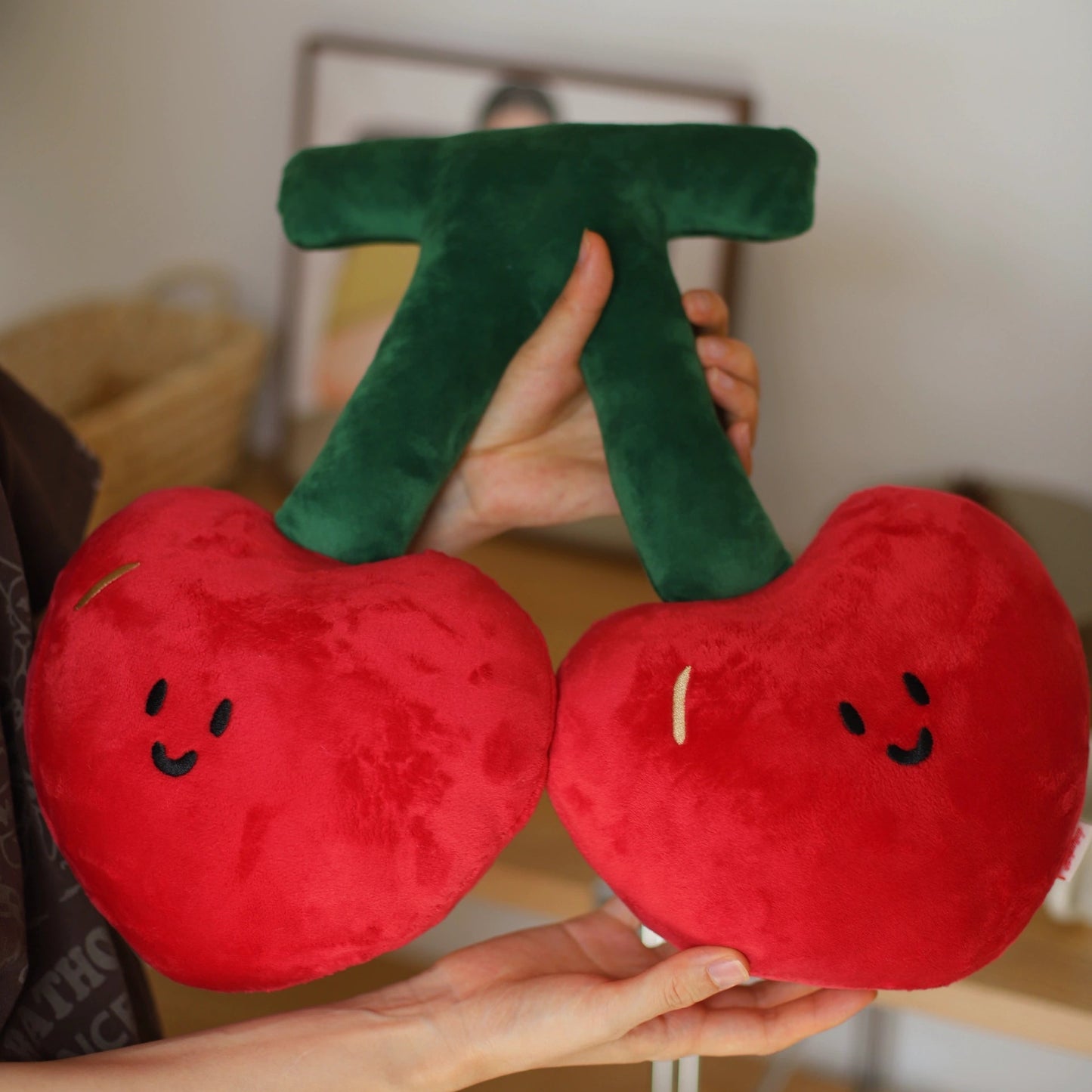 Plush cherries held by a person with a blurred background