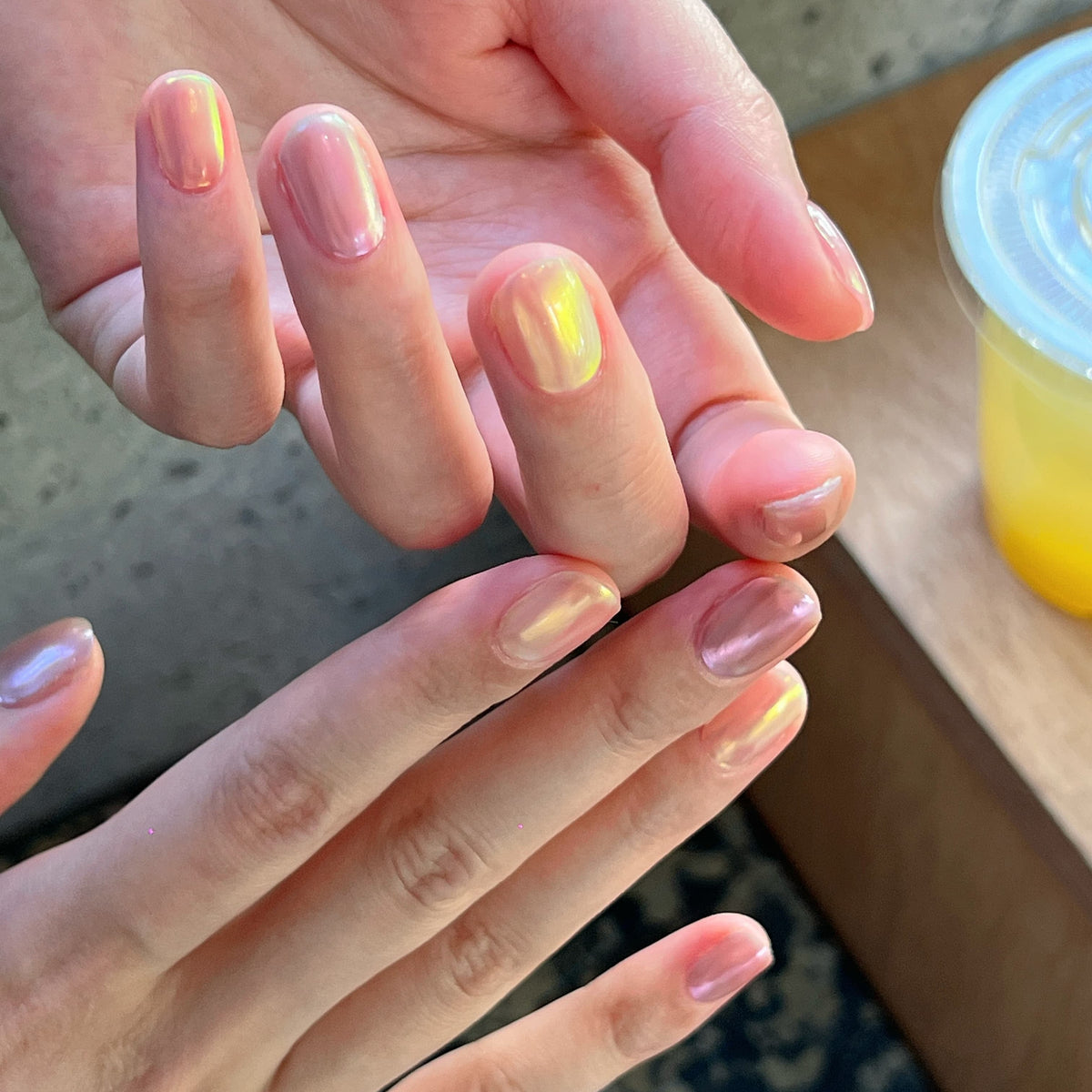 Close-up of hands with light pink nail polish on a blurred background