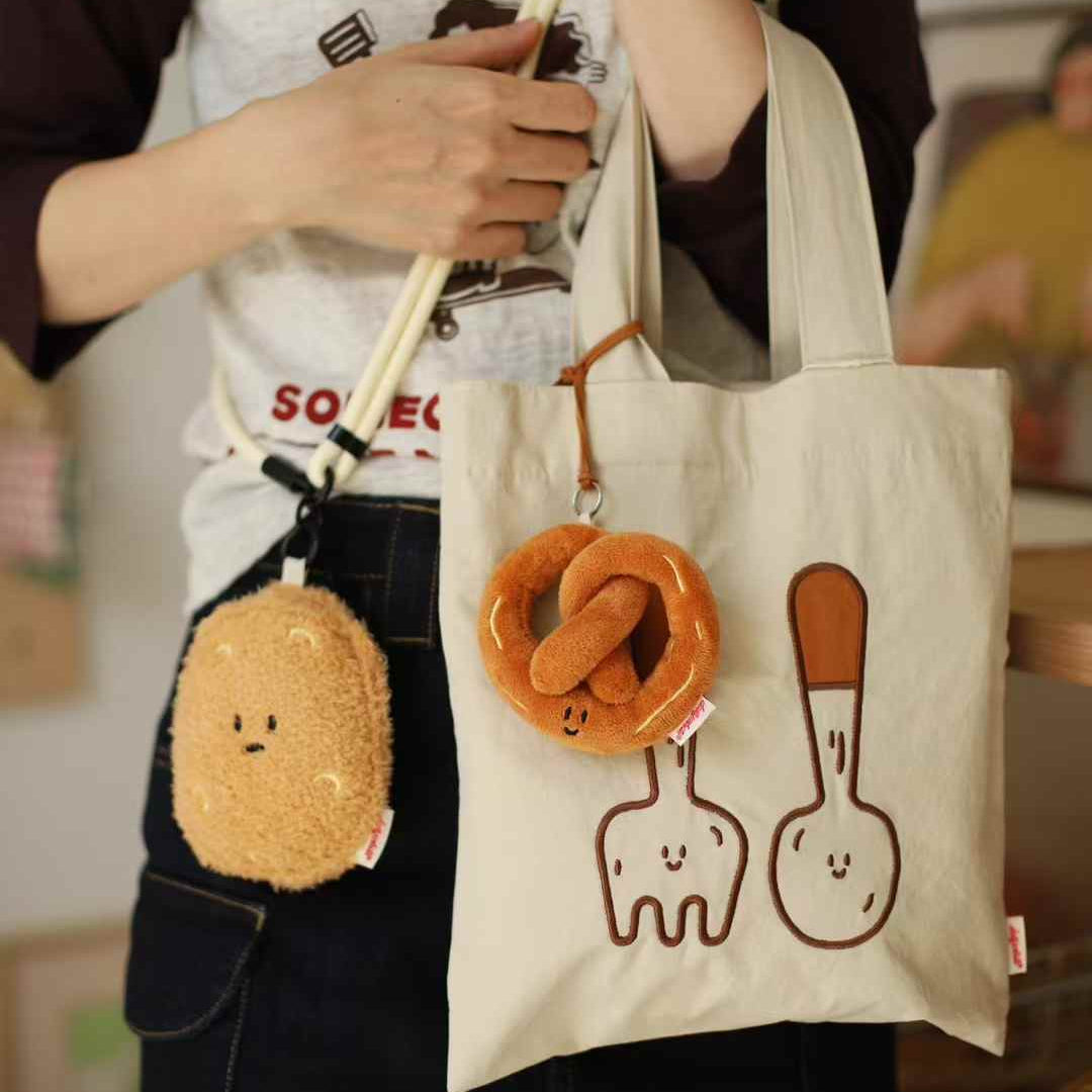 Person holding a tote bag with cartoon characters and plush keychains.