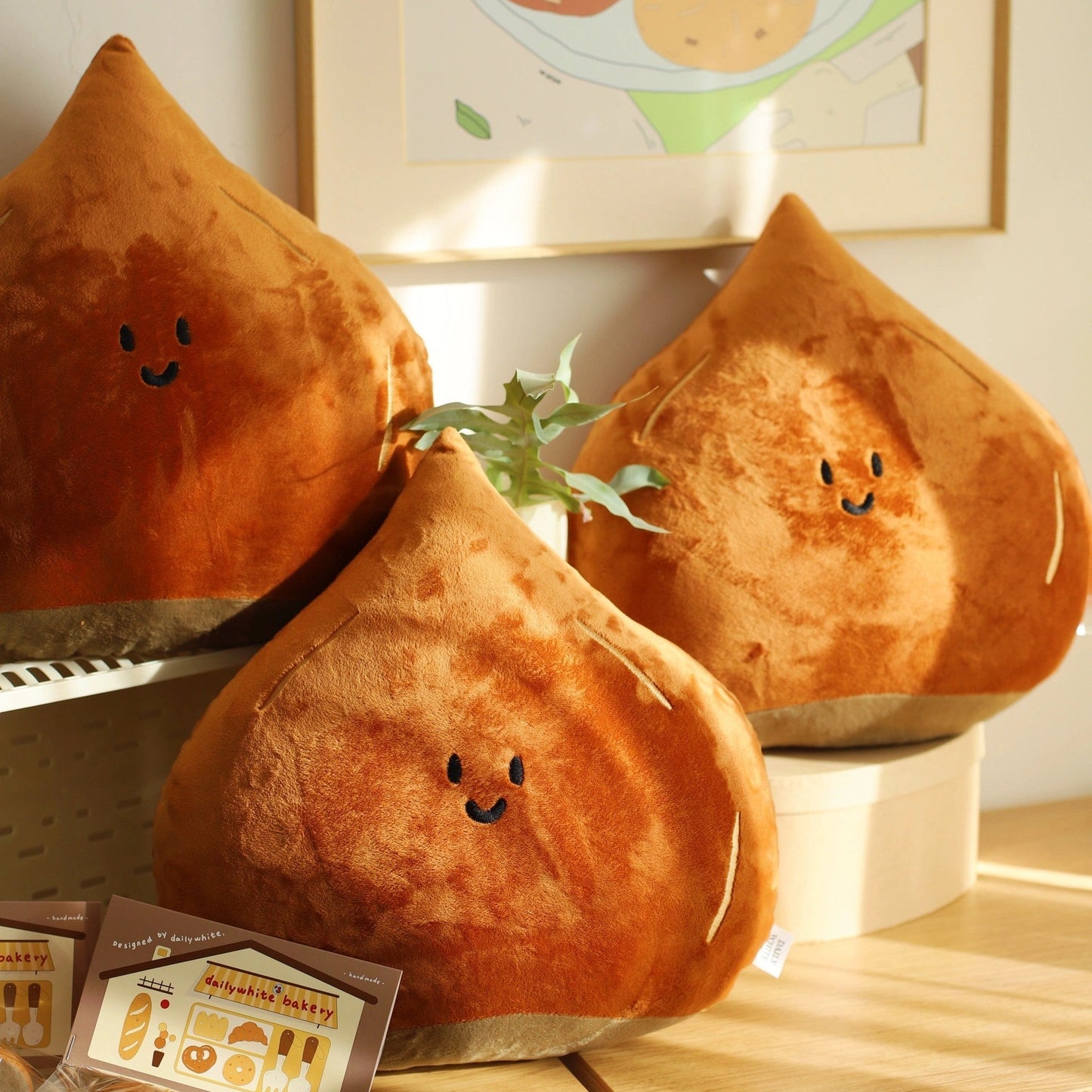 Three plush chestnut-shaped cushions with smiling faces on a wooden surface.