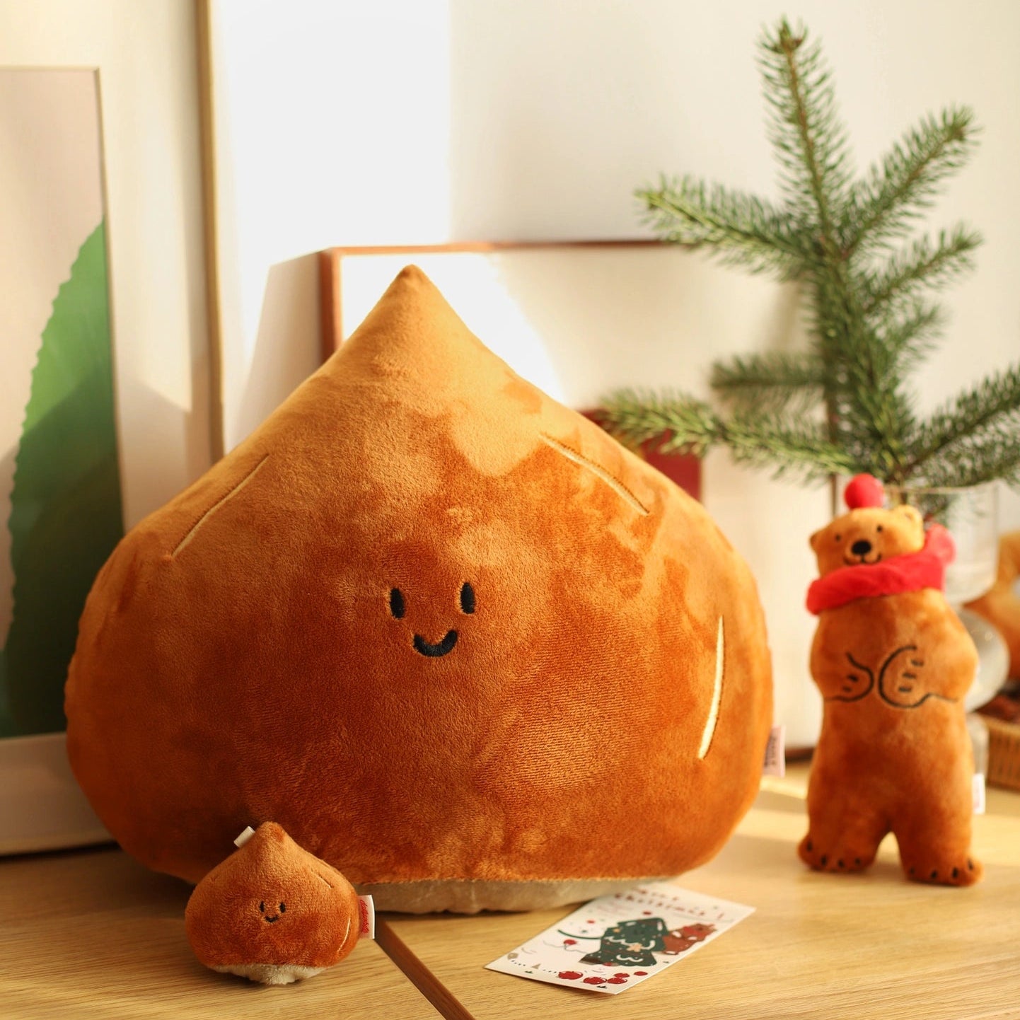 Plush chestnut-shaped toy on a wooden surface with a small bear plush toy and decorative cards.