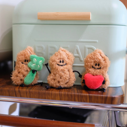 Three small plush figures with accessories on a bread box