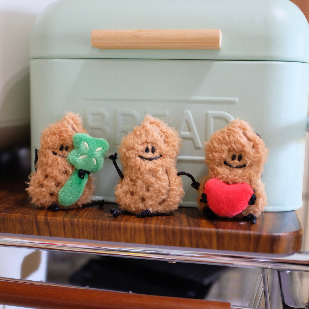 Three small plush figures with accessories on a bread box