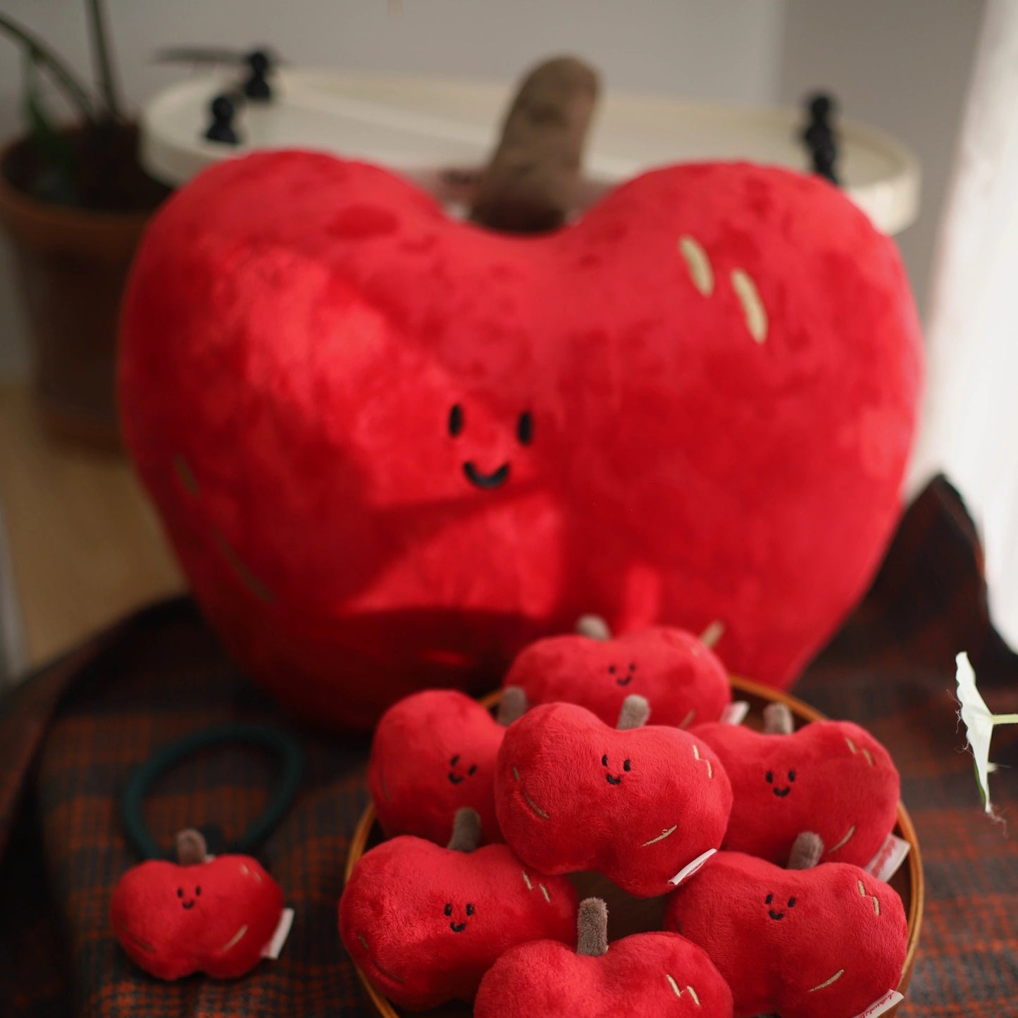 Red plush apples with smiling faces on a wooden surface