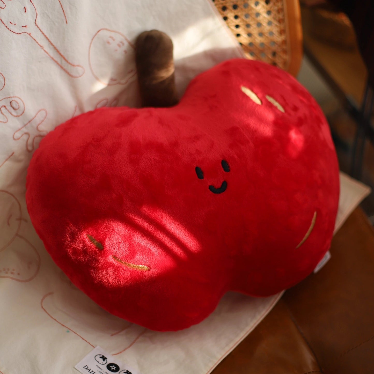 Red heart-shaped plush toy with a smiley face on a light-colored surface.
