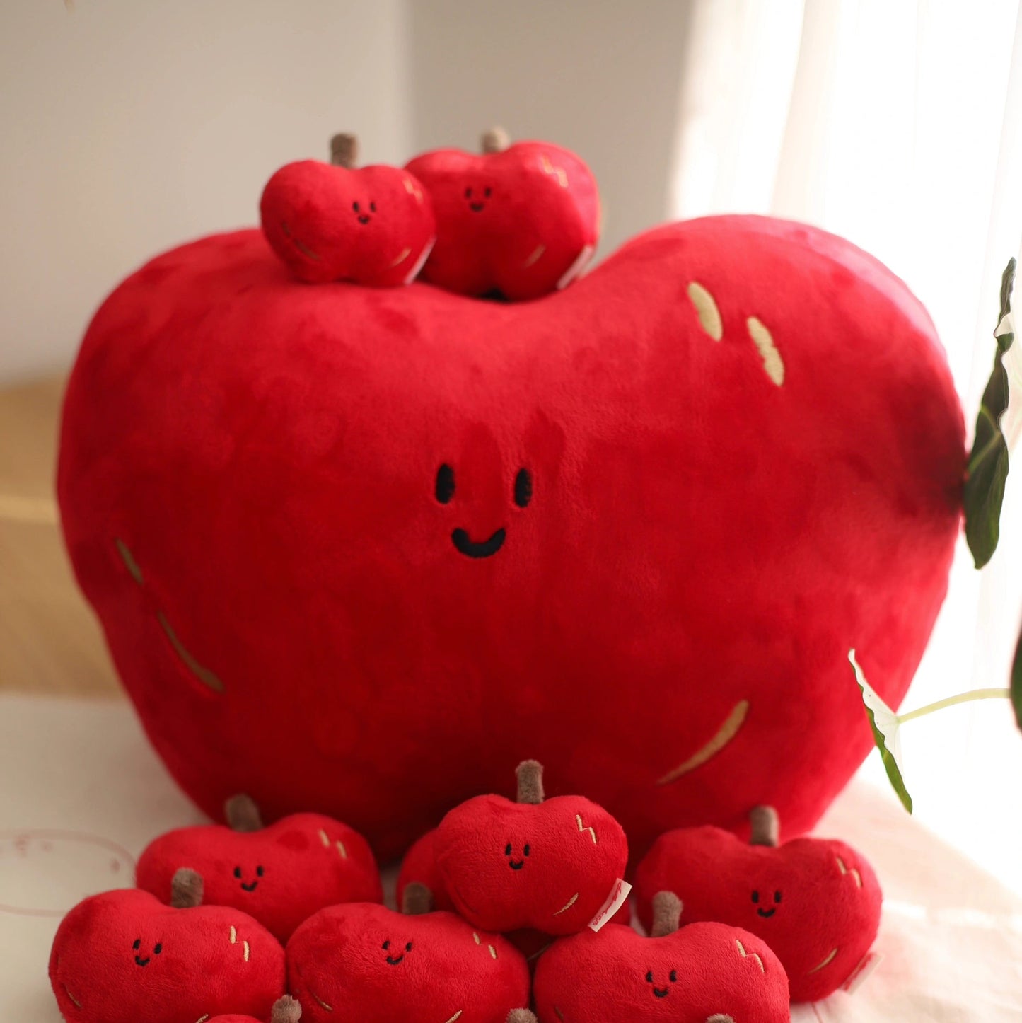 Red plush apples with smiling faces on a light surface