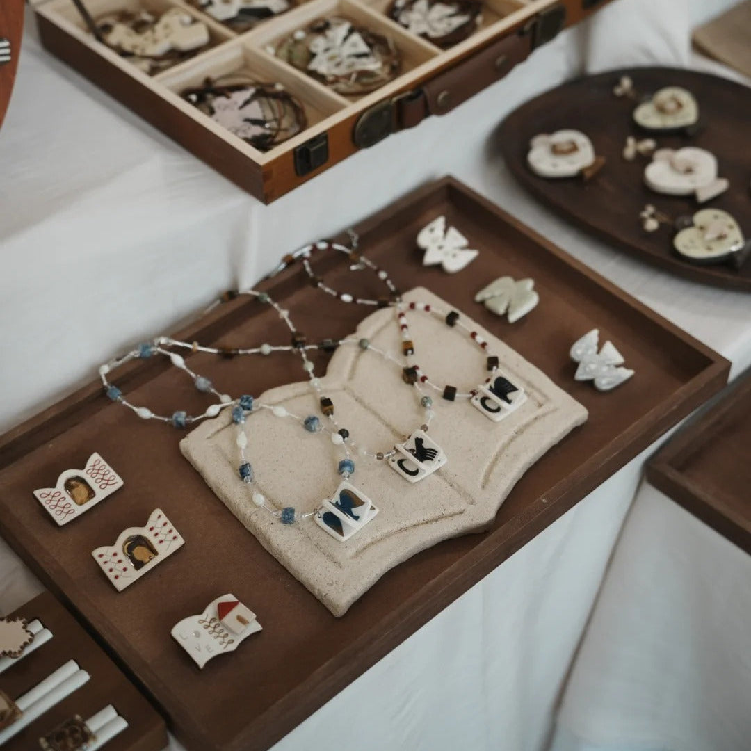 Jewelry set with necklaces and pendants displayed on a wooden tray and in an open jewelry box.