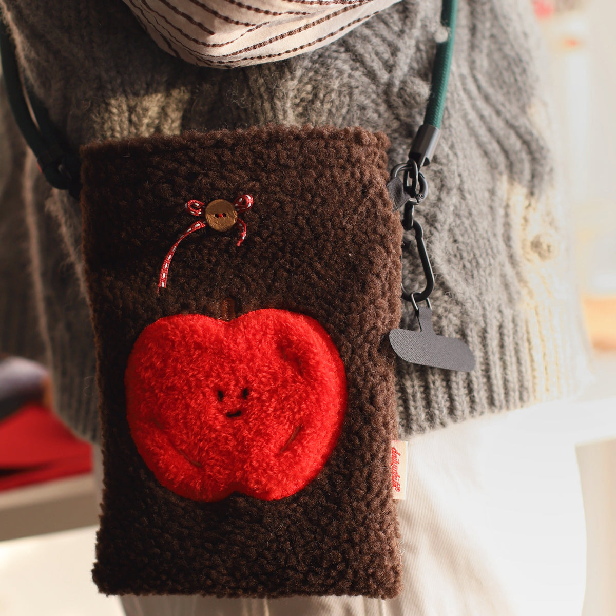 Brown textured pouch with a red apple design on a blurred background