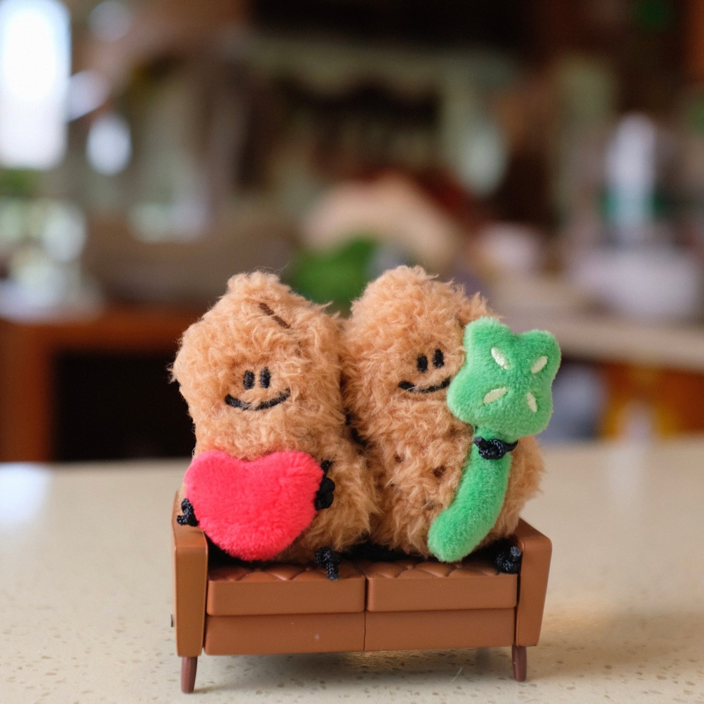 Two plush toys sitting on a small wooden platform with a blurred indoor background
