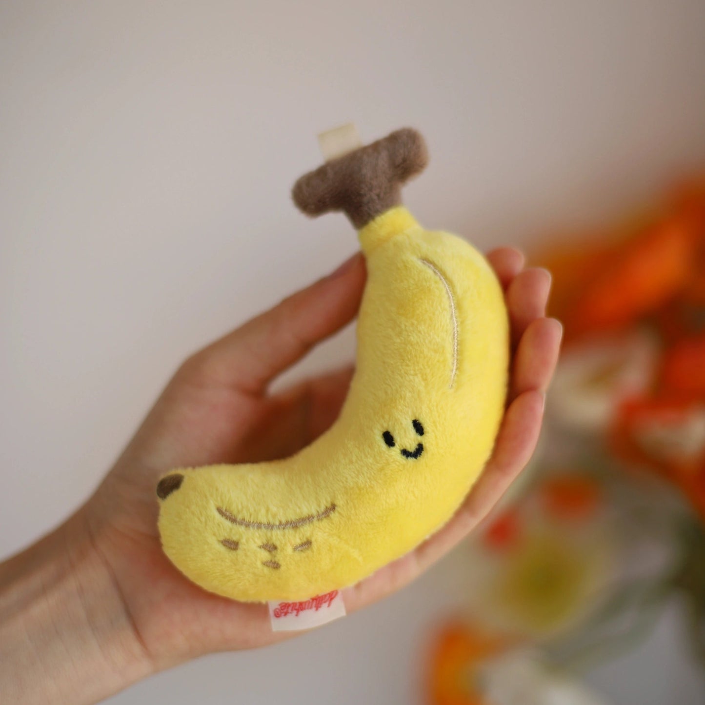Plush banana toy held in a hand with a blurred background