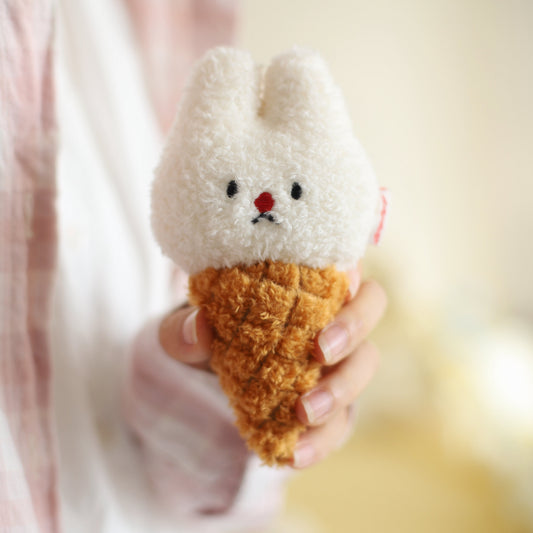 Plush toy shaped like a rabbit in an ice cream cone held by a person.