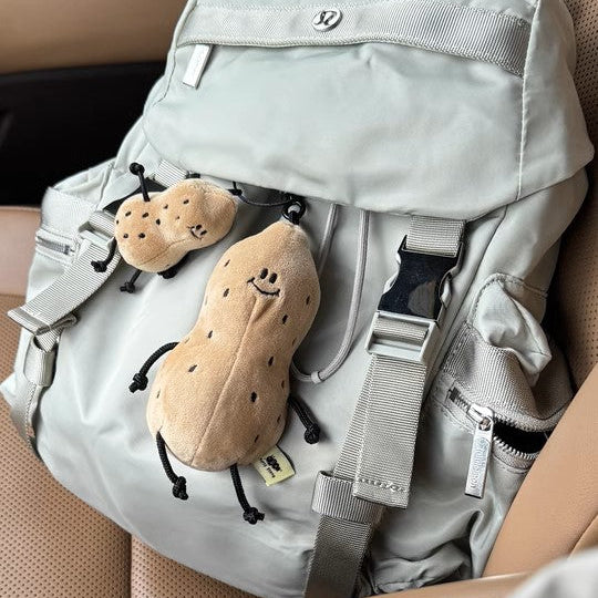 Light gray backpack with cartoonish peanut design on a beige car seat