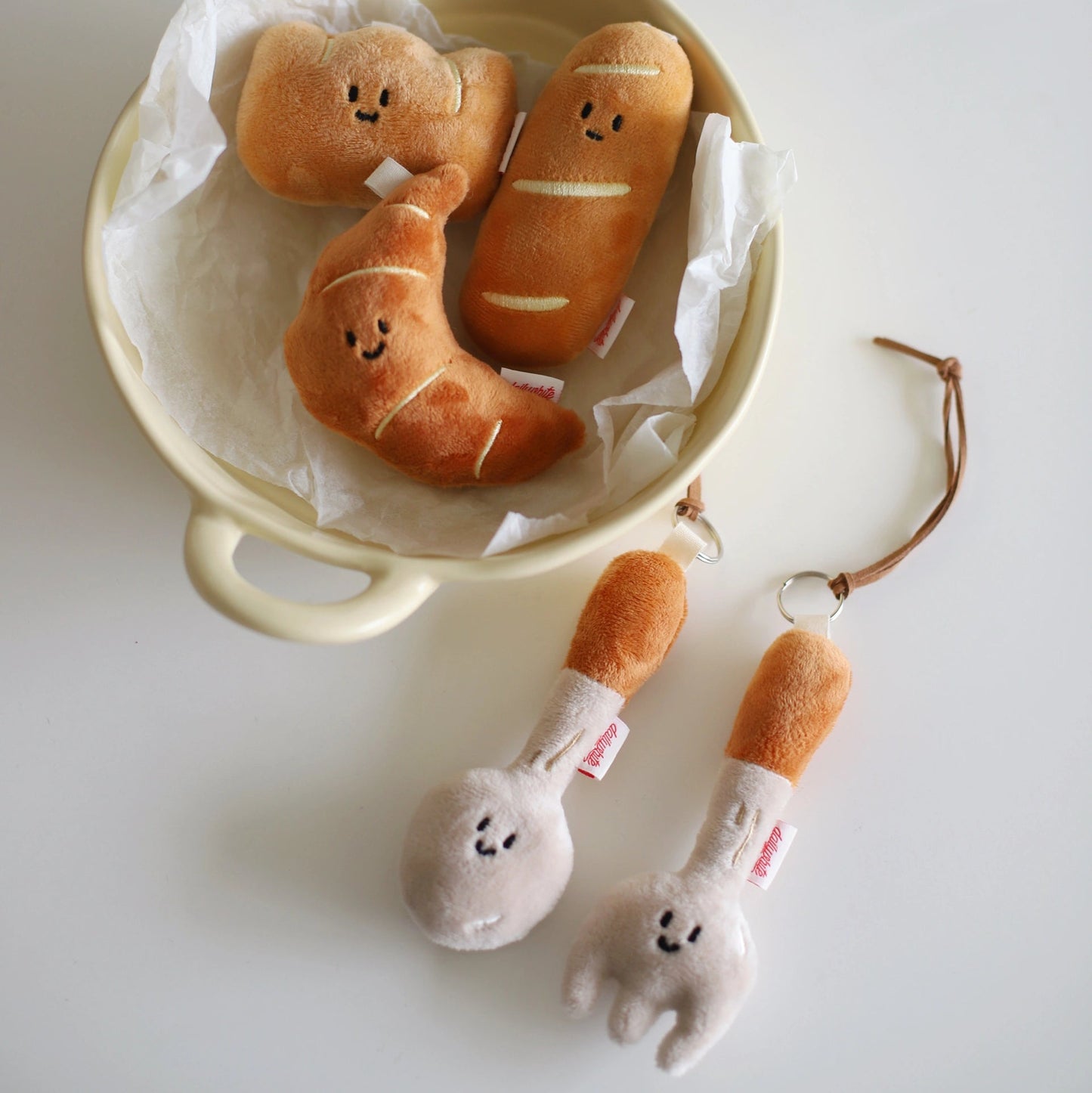 Plush toys resembling bread and a fork on a white surface