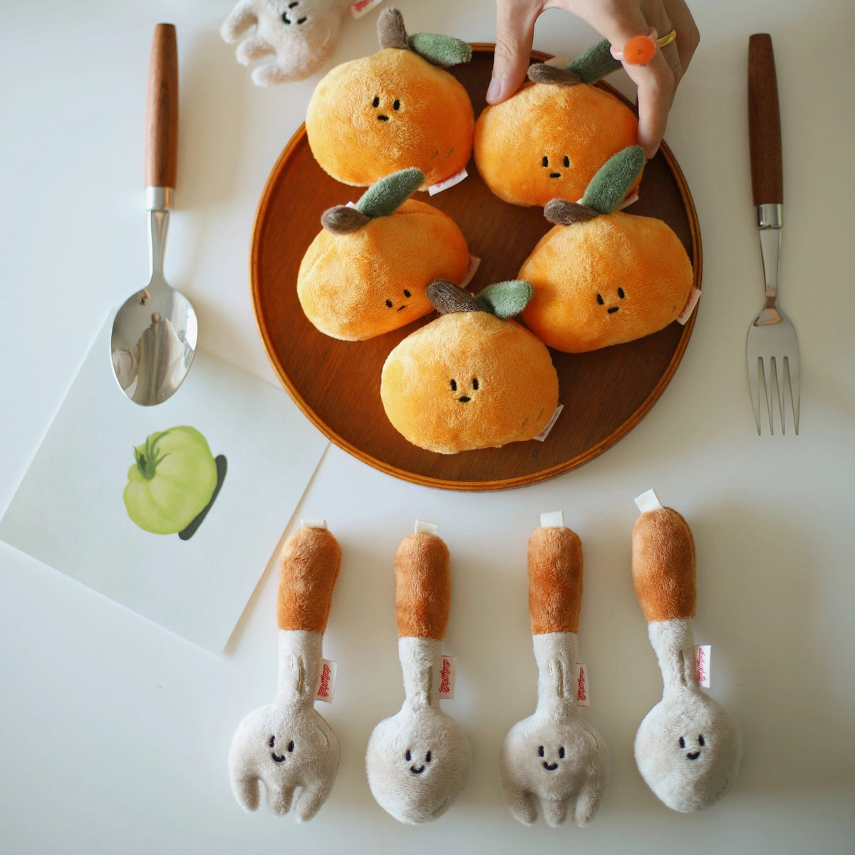Plated oranges with faces, surrounded by toy vegetables on a white background