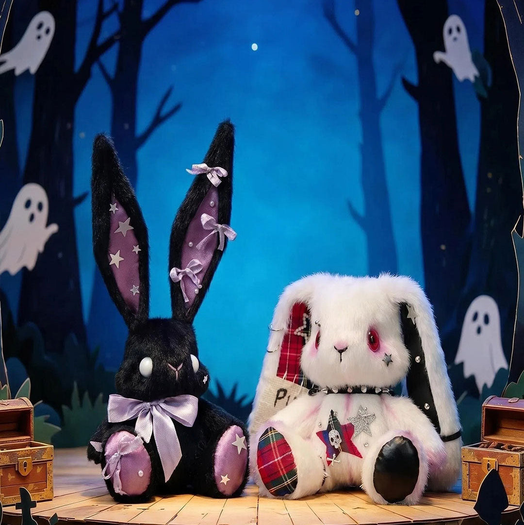 Two plush bunnies sitting on a wooden platform with a spooky forest background.