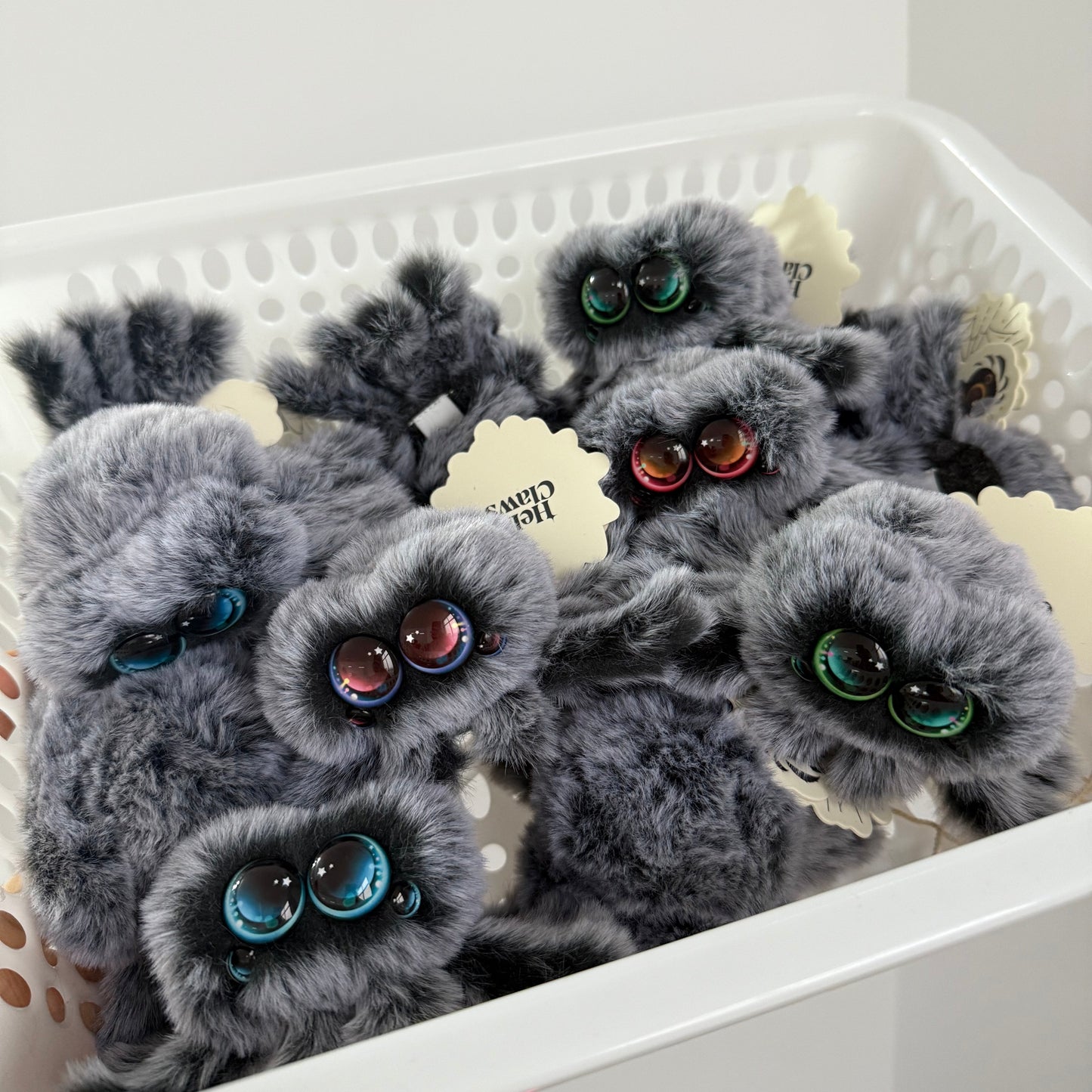 Gray fluffy phone cases with decorative elements on a white surface