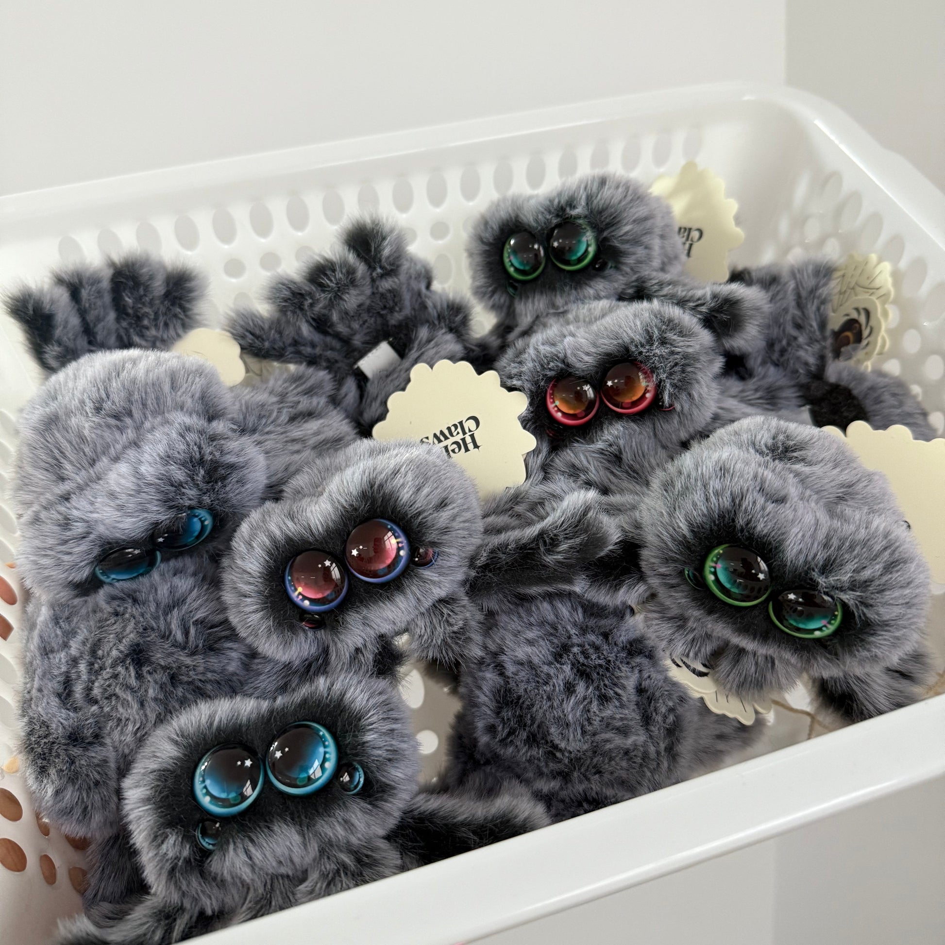 Gray fluffy phone cases with decorative elements on a white surface