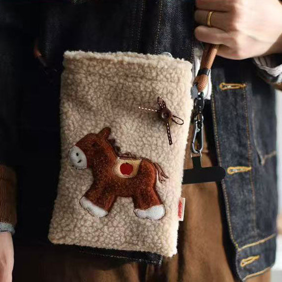 Hand holding a small pouch with a horse design and fur texture.