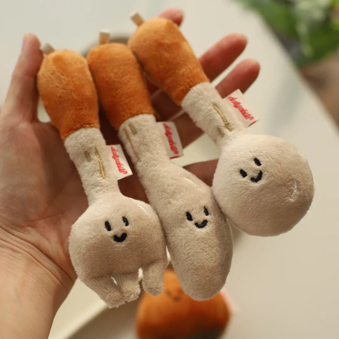 Plush toy carrots with smiling faces held in a hand on a light background