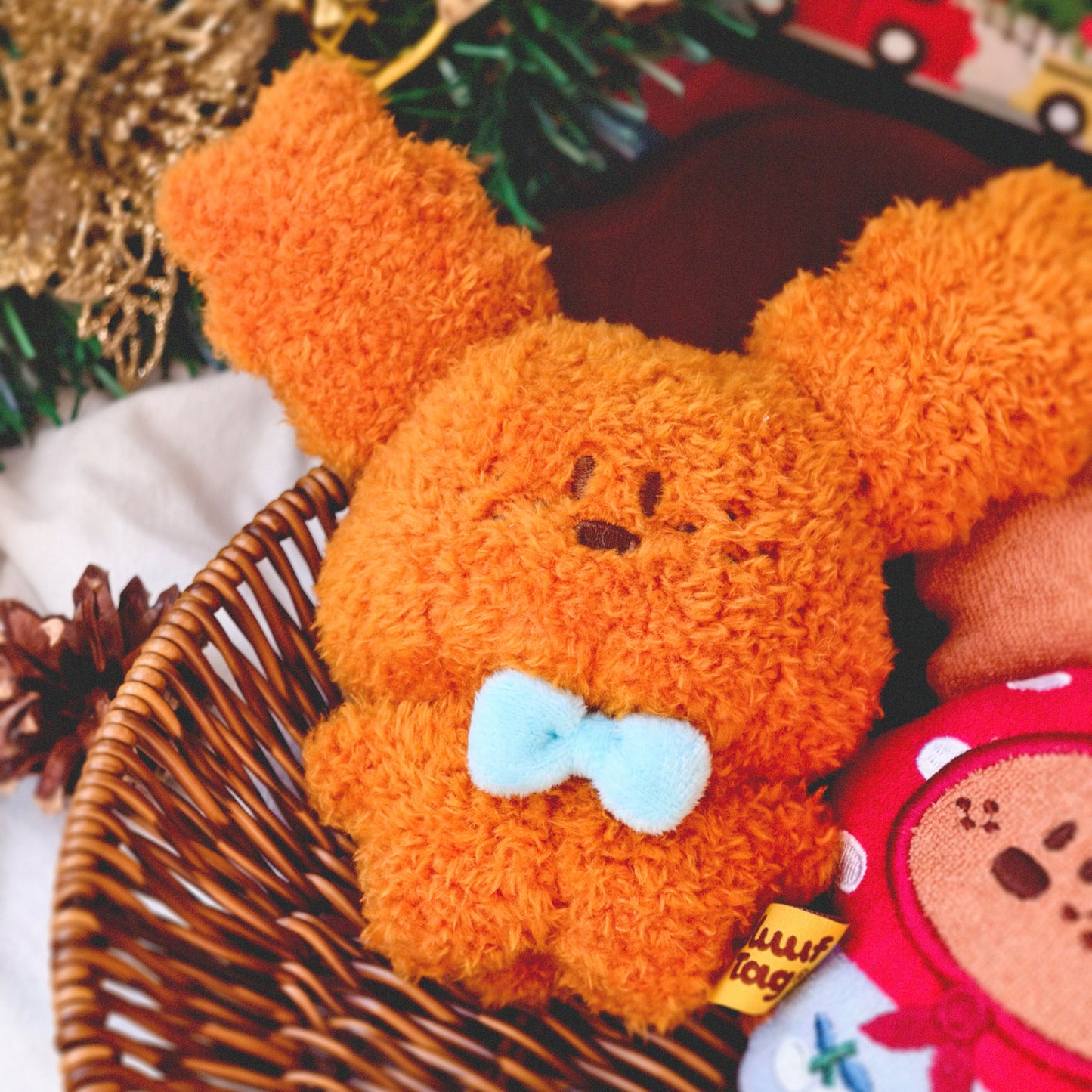 Plush toy resembling a bear with a bow tie in a festive setting with Christmas decorations.