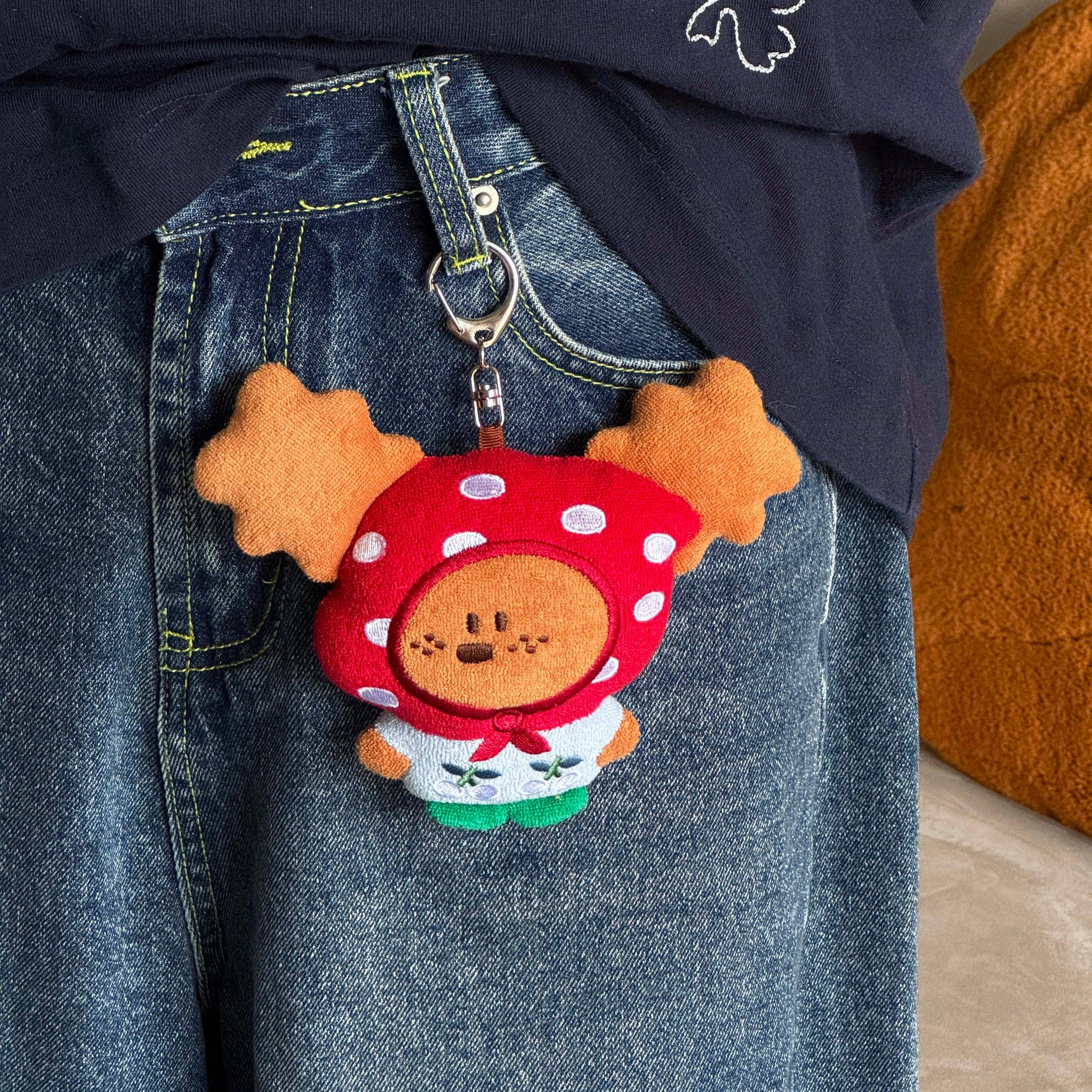Keychain shaped like a cartoon character with a mushroom hat attached to a blue denim jacket.
