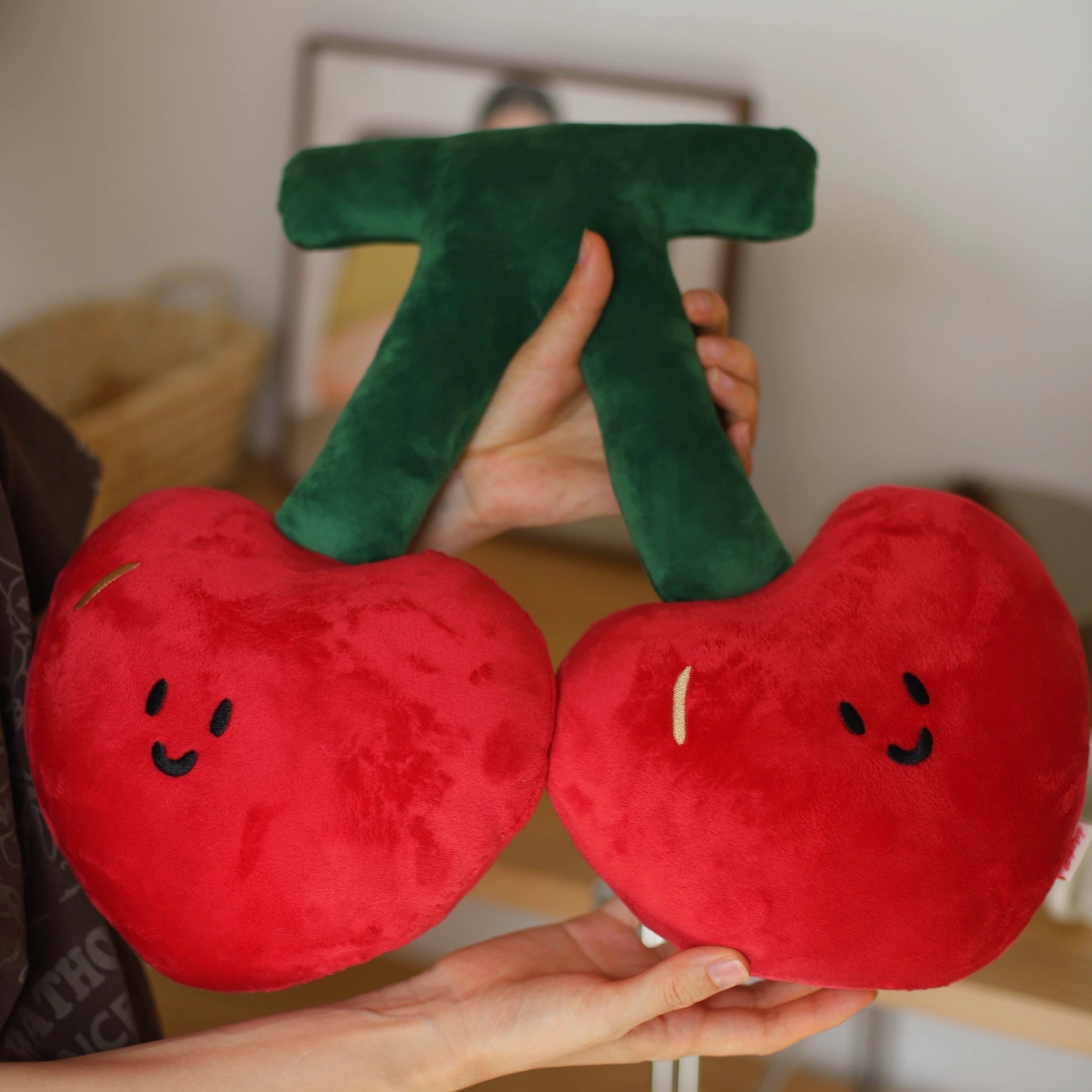 Plush cherries held by a person with a blurred background