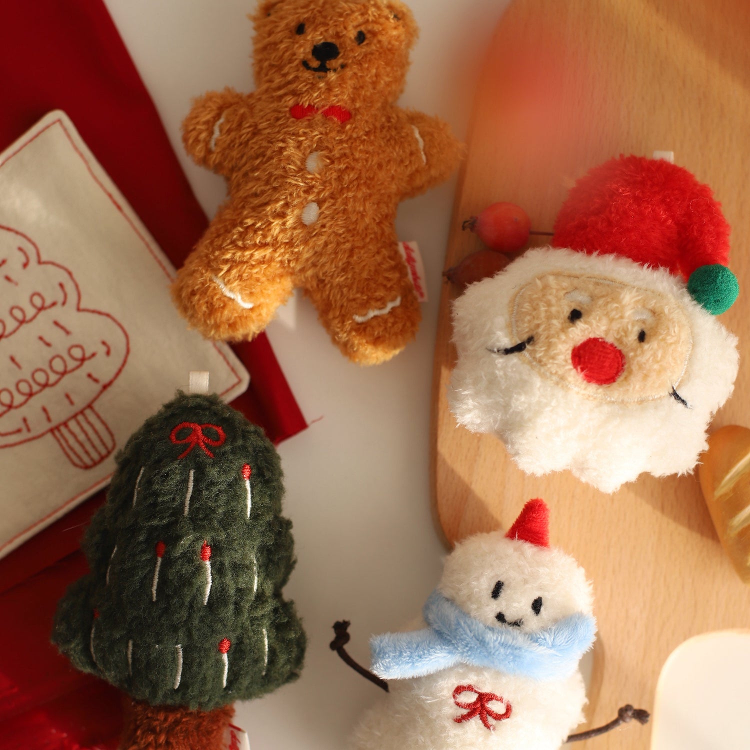 Set of Christmas-themed plush toys including a bear, gingerbread man, tree, and snowman on a wooden surface.