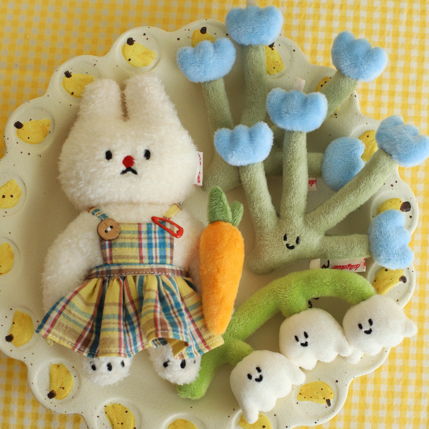 Plush toy rabbit with a carrot and decorative elements on a yellow checkered background