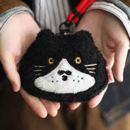 Black pouch with a cat face design held in hands
