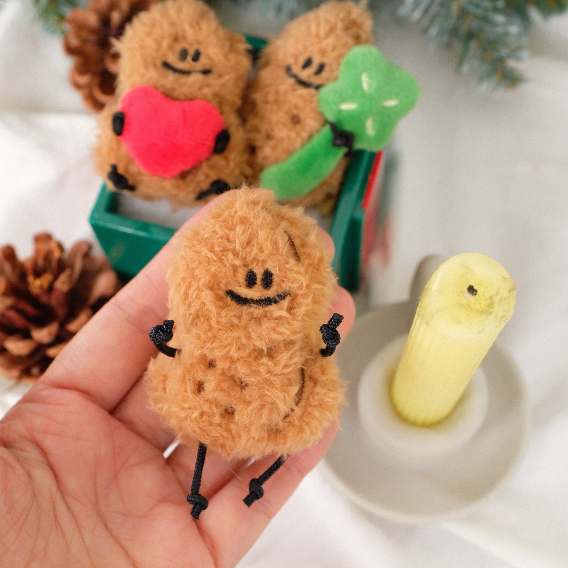 Small brown plush toy held in a hand with decorative items in the background
