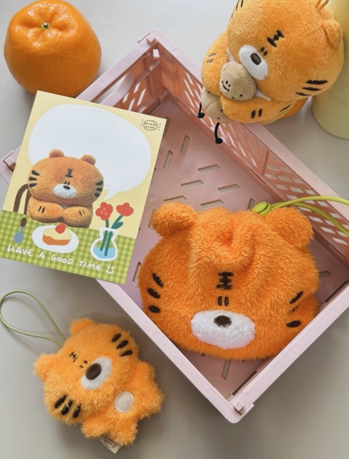 Plush tiger toys and a card with a tiger design on a light surface.