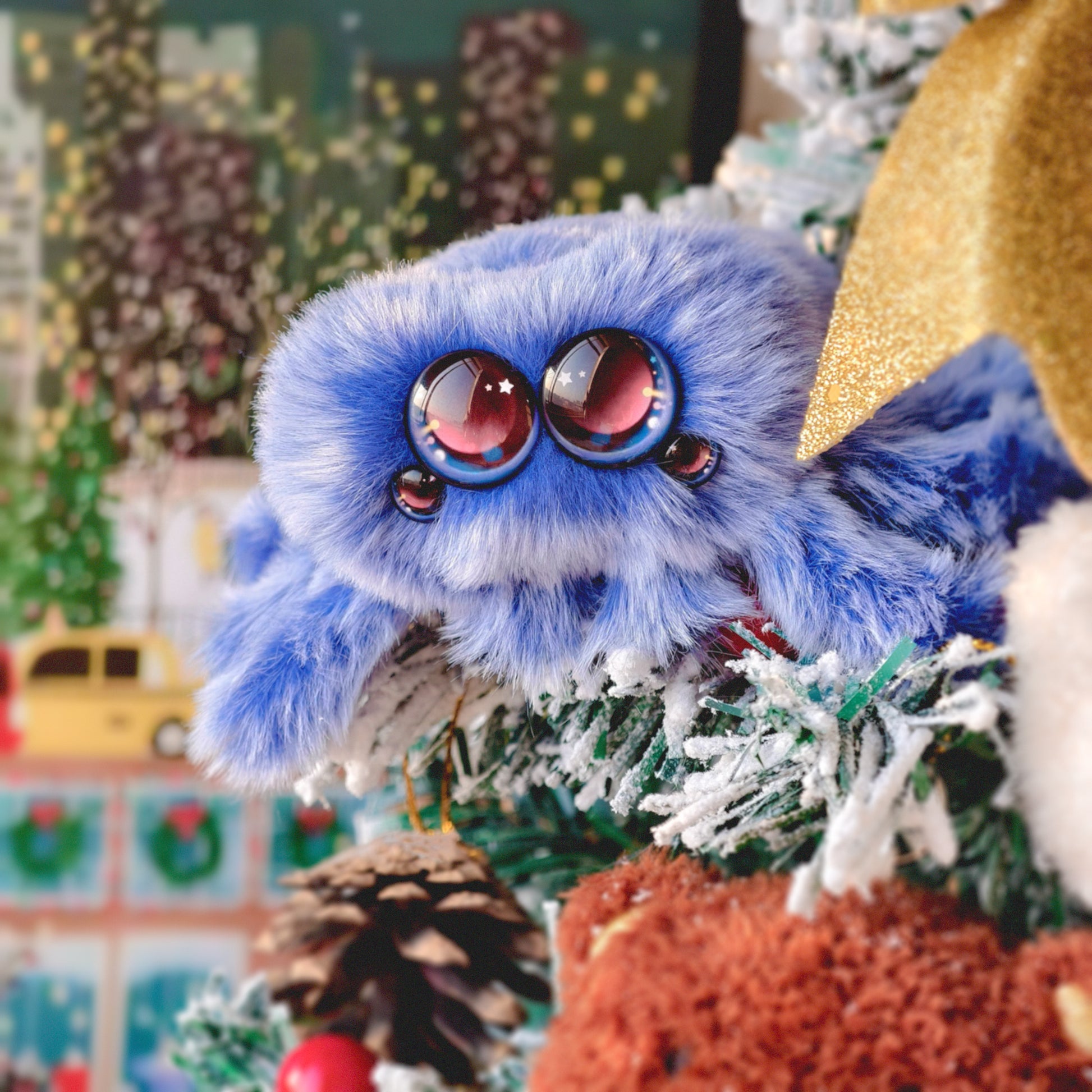Blue plush toy with large red eyes on a Christmas tree with ornaments and lights.