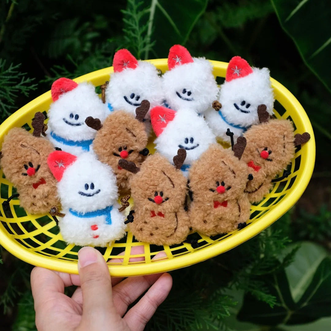 Hand holding a yellow basket with small plush toys resembling cartoonish chickens and sheep against a green leafy background.