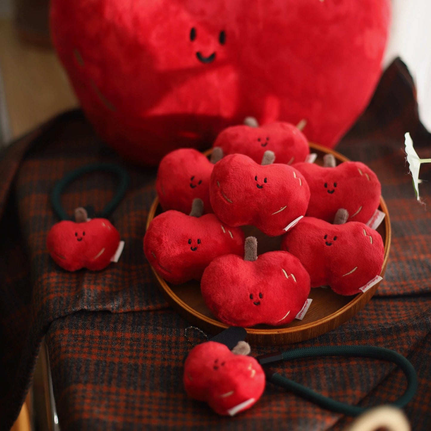 Red plush apples with smiling faces on a wooden surface