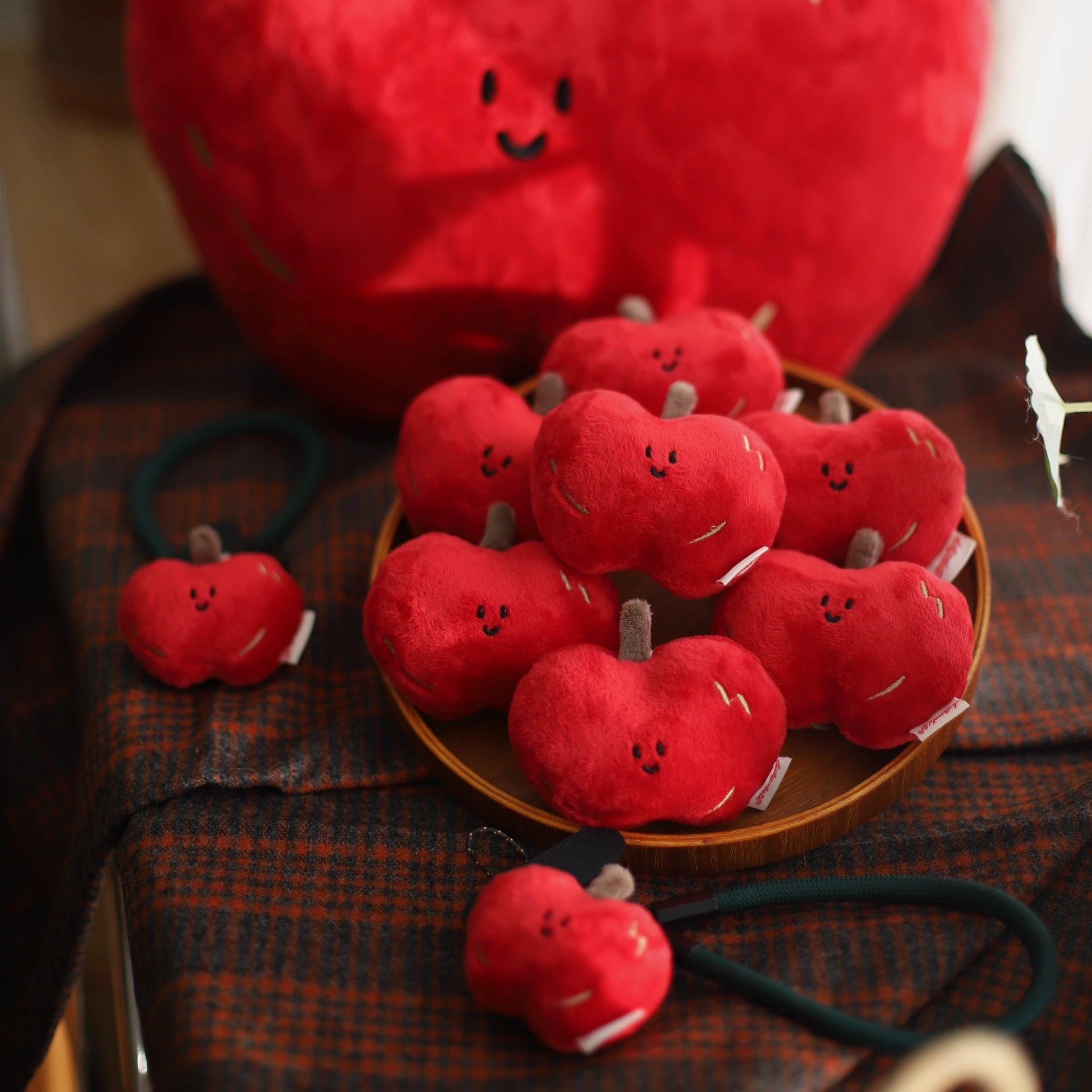Red plush apples with smiling faces on a wooden surface