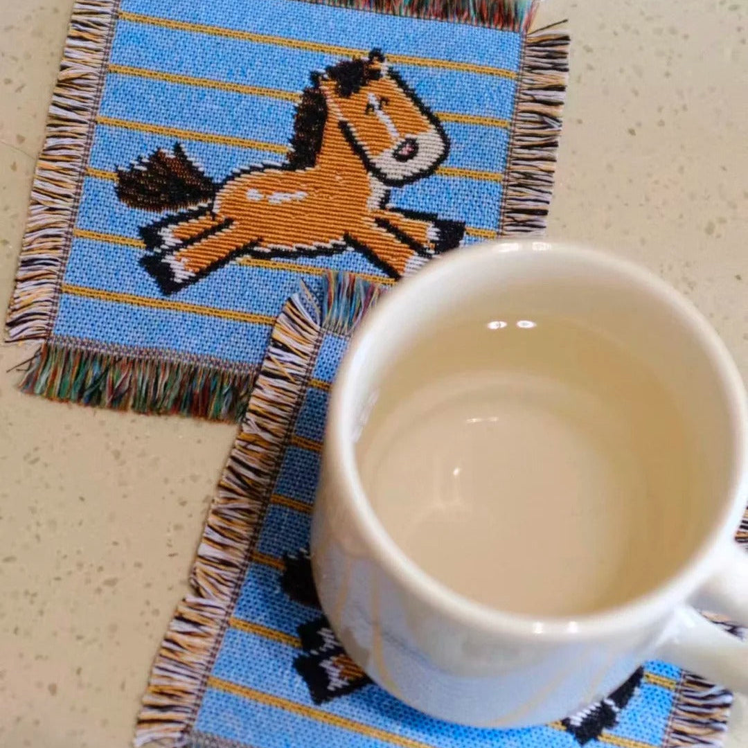 Coaster with horse design on a table next to a mug