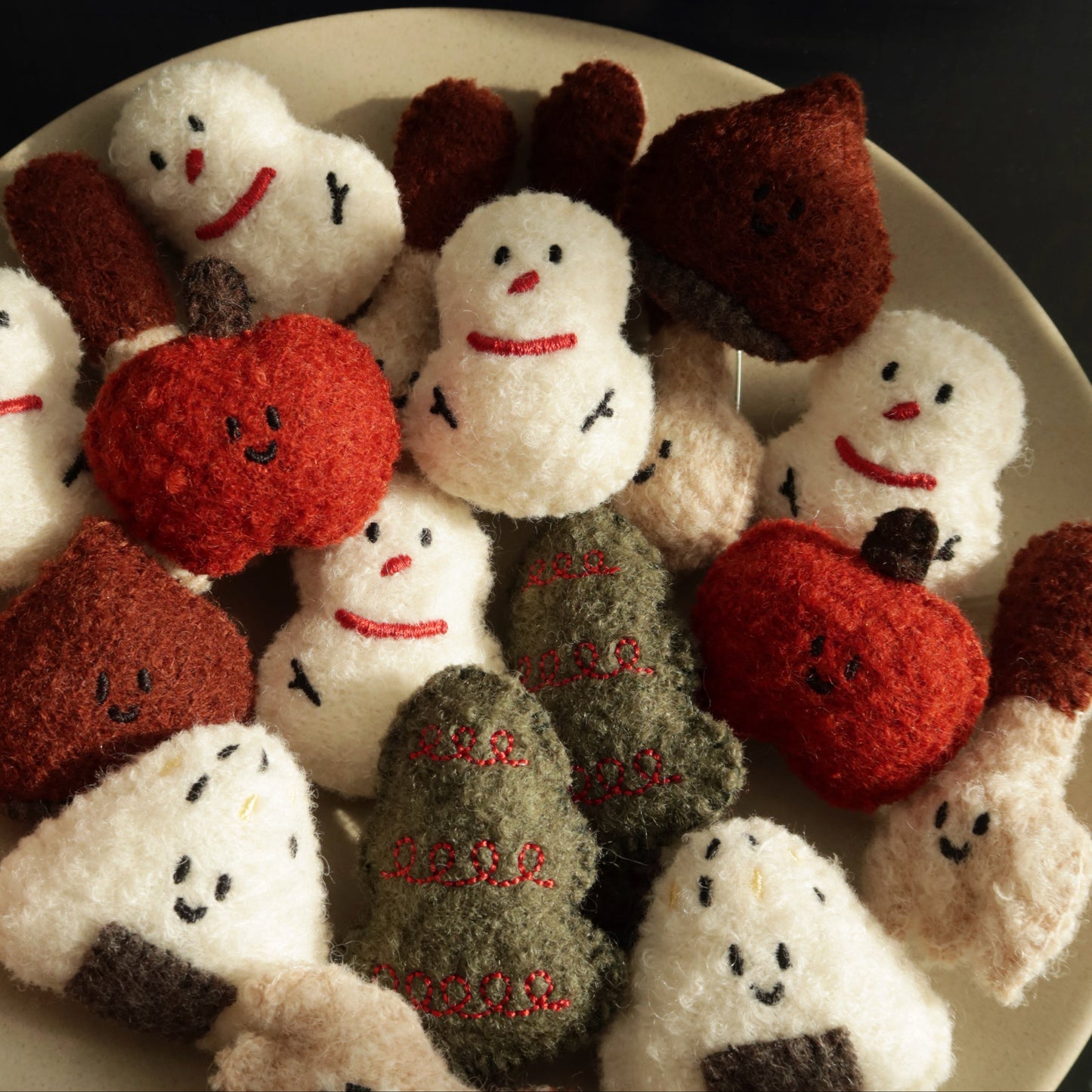 Collection of handmade plush toys resembling snowmen and pumpkins on a dark background
