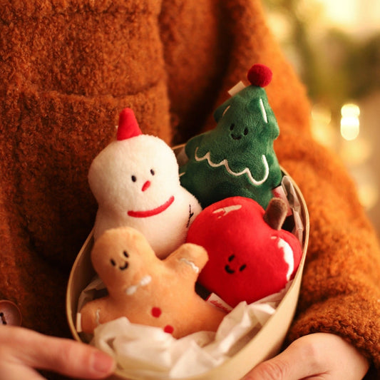 Person holding a small bowl with Christmas-themed plush toys against a blurred background.