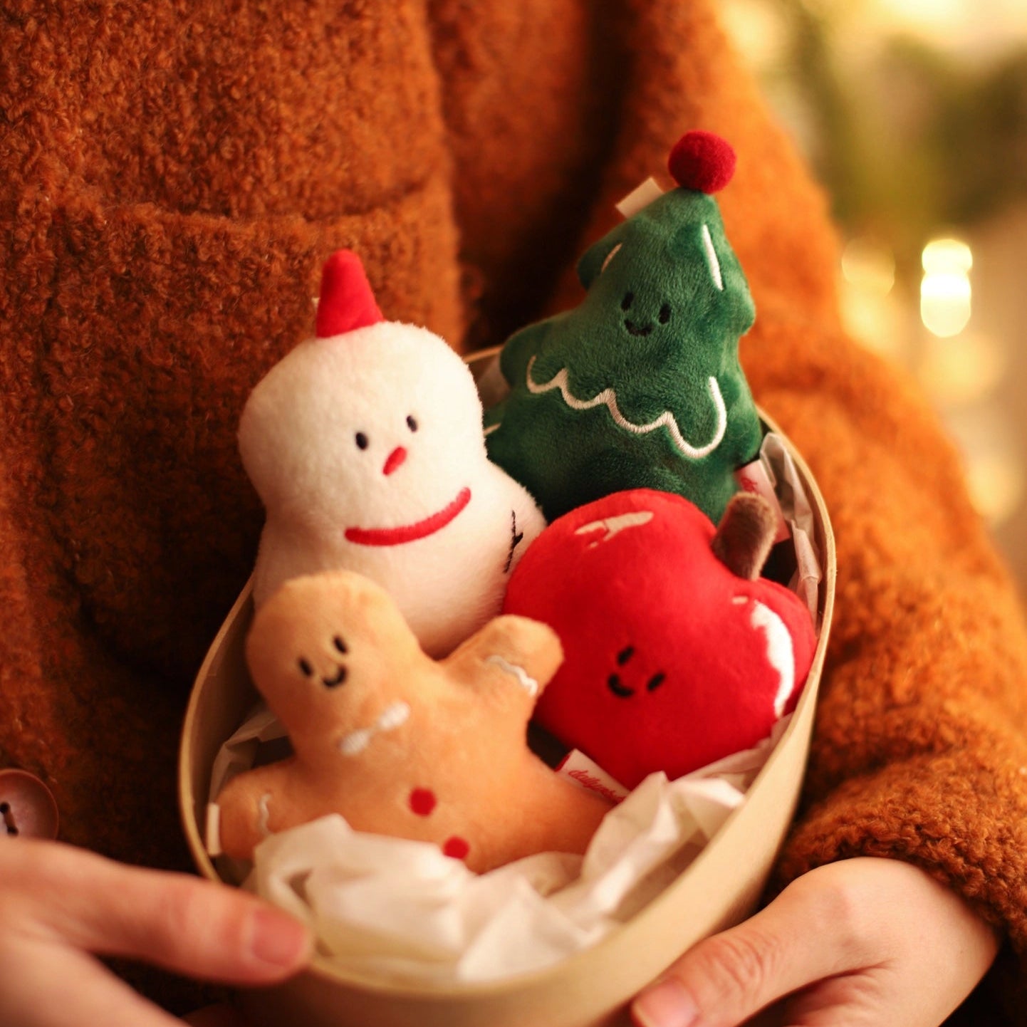 Person holding a small basket with Christmas-themed plush toys.