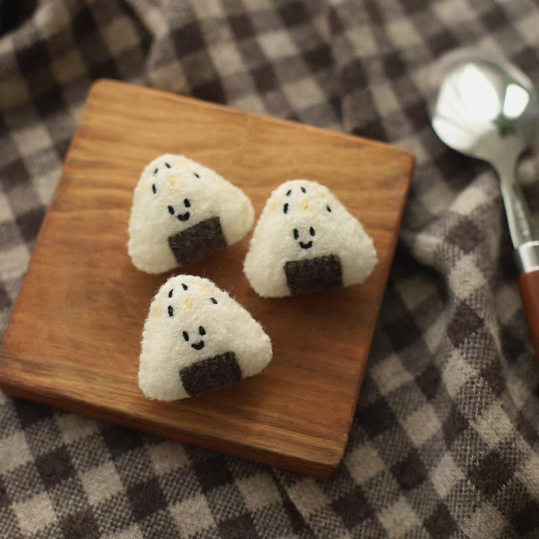 Three rice balls with faces on a wooden board on a checkered fabric background