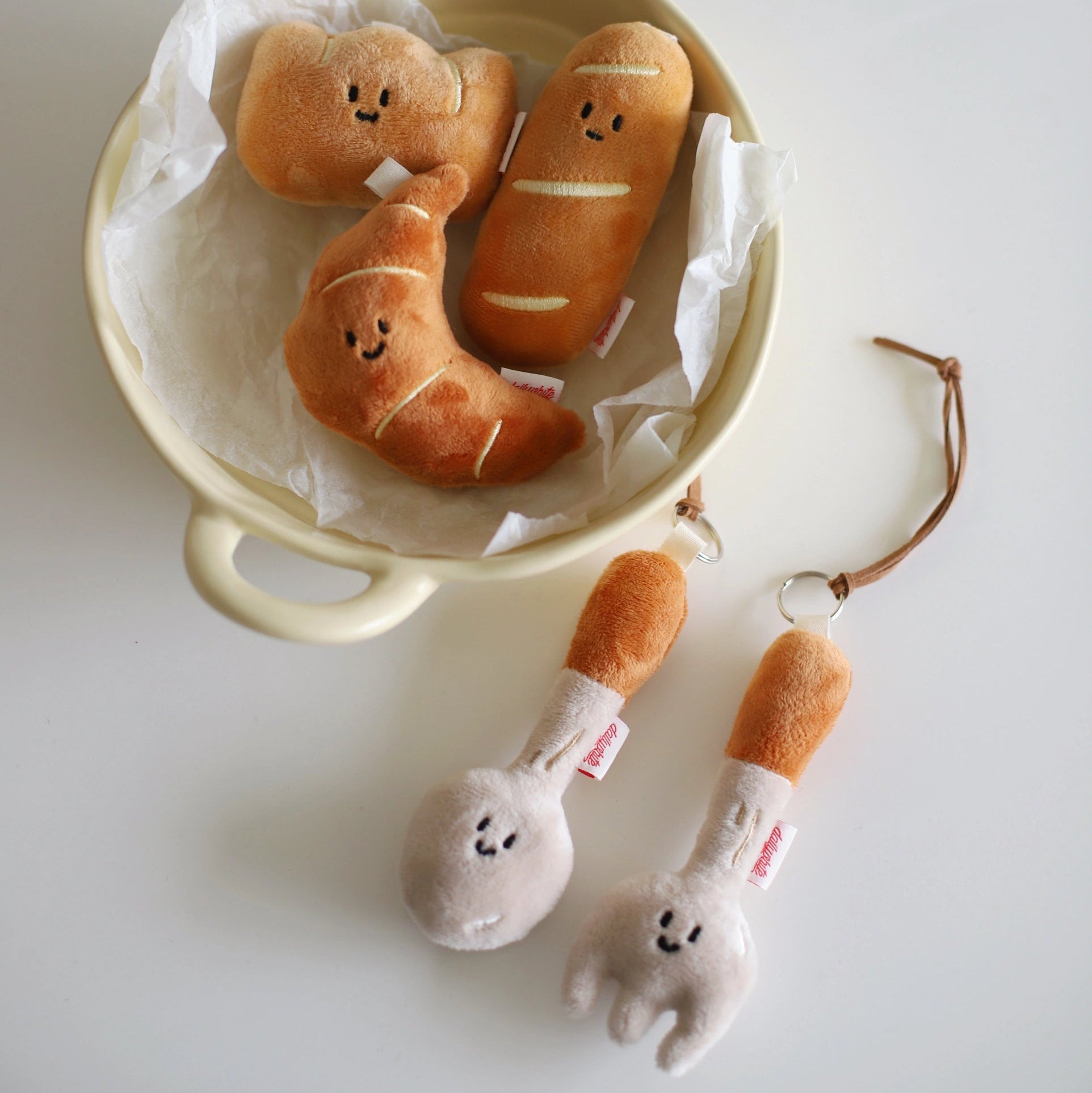 Plush toys resembling bread and a fork on a white surface
