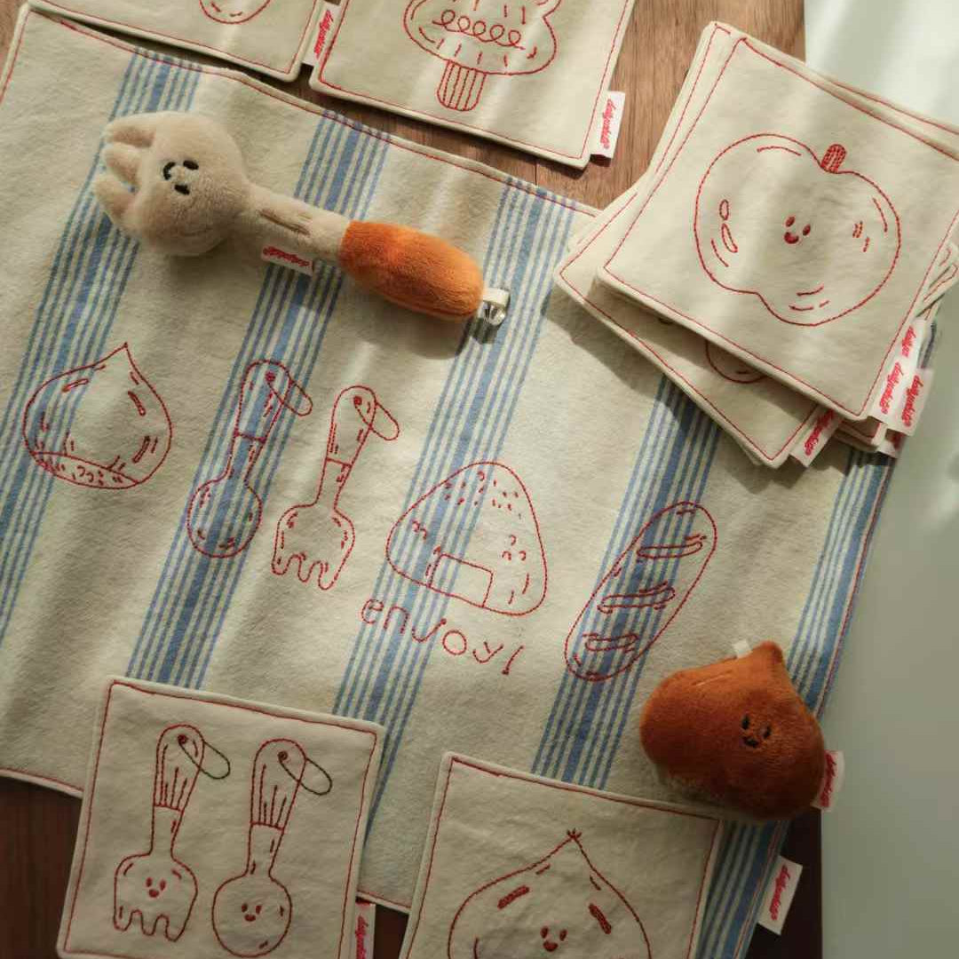 Embroidered placemats with cartoon designs on a tablecloth.